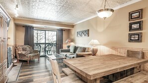 Un vaste espace de vie comprenant une table à manger en bois, un canapé et un fauteuil à motifs.