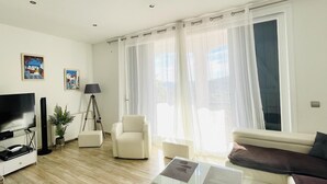 A modern living room with a flat-screen TV, a sofa, a coffee table, and a floor lamp. - Villa Loralil by Costabravaway (calonge)