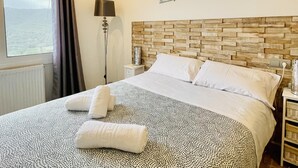 A hotel room with a bed, a nightstand, a lamp, and a view of the sea. - Villa Loralil by Costabravaway (calonge)