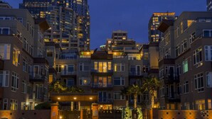 A multi-story residential building with balconies, a gated entrance, and a parking area. - Steps to Pike Place 2BD Condo Water Courtyard View (Seattle)