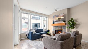 A modern living room with a sofa, armchairs, a fireplace, and large windows. - Steps to Pike Place 2BD Condo Water Courtyard View (Seattle)