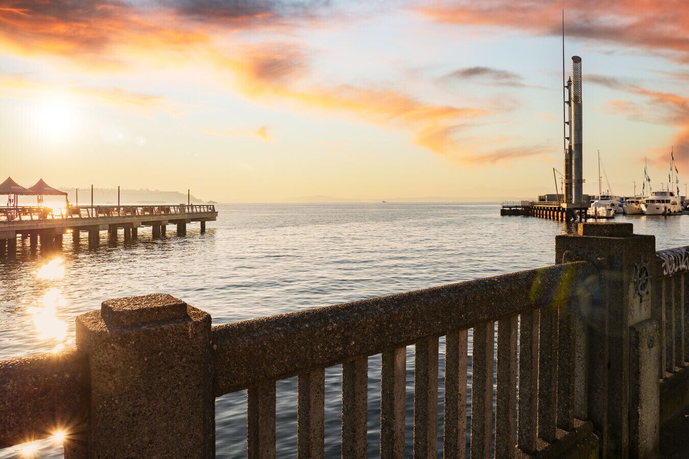 A pier extending into calm waters with a sunset in the background.