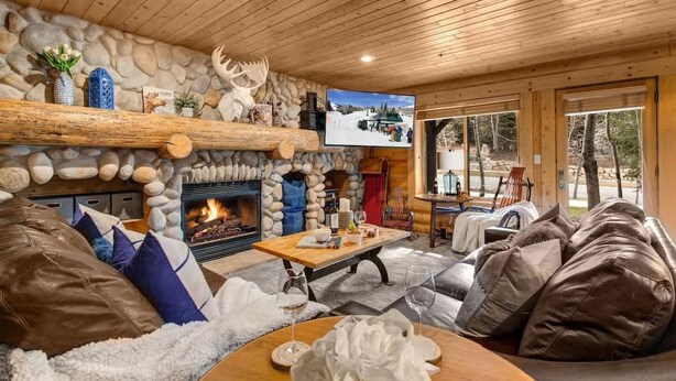 A cozy lodge interior with a stone fireplace, wooden ceiling, and a television mounted on the wall. - Abode at Black Bear #104, private hot tub, pool & gym, Deer Valley (Park City)
