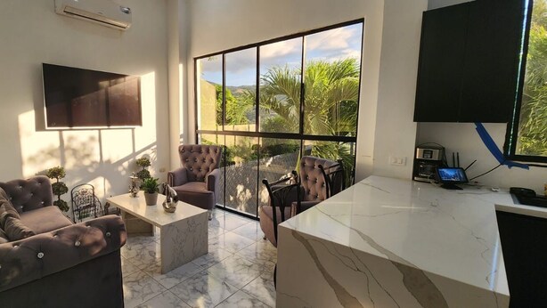 A modern living room with a sofa, armchairs, a coffee table, and a TV mounted on the wall.