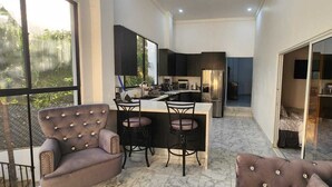 A compact kitchen with modern appliances, a dining area with two chairs, and a large window providing a view of greenery.