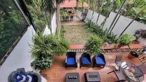 A rooftop patio with two blue lounge chairs, a small table, and various potted plants.