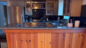 Eine Küche mit Holzschnitzereien, einer Granitarbeitsplatte, Edelstahlgeräten und einem Holzboden.