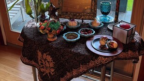 Ein Tisch mit einer verzierten Tischdecke, einer Blumenvase und verschiedenen kleinen Geschirr und Kerzen.