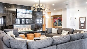 Una sala moderna con un sofá modular, una chimenea y un televisor.