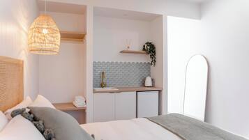Ein modernes Schlafzimmer mit Bett, Nachttisch und einer kleinen Küchenzeile.
