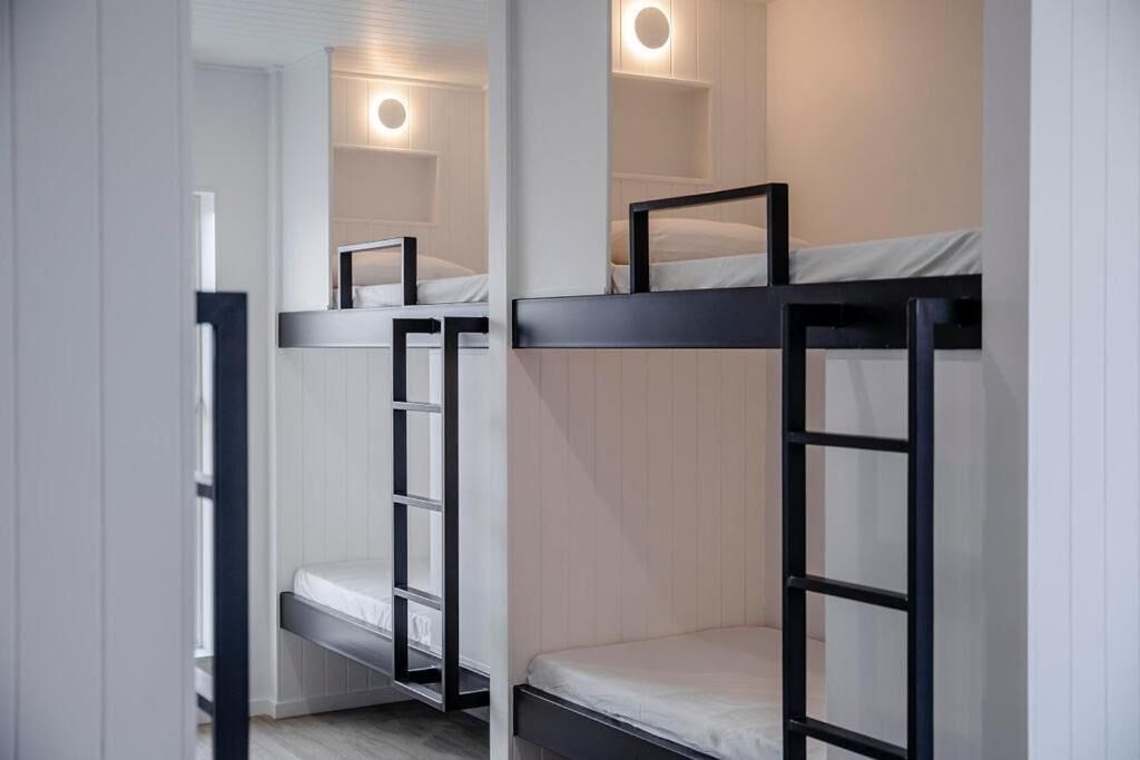 A bunk bed room with a mirror and a shelf.
