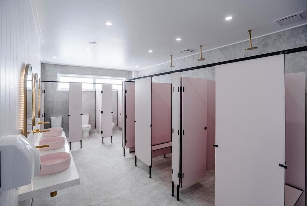 Un baño moderno con varios lavamanos, inodoros y taquillas.