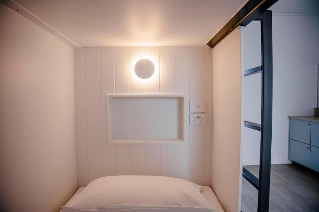 A bedroom with a bed, a wall-mounted light, and a power outlet.