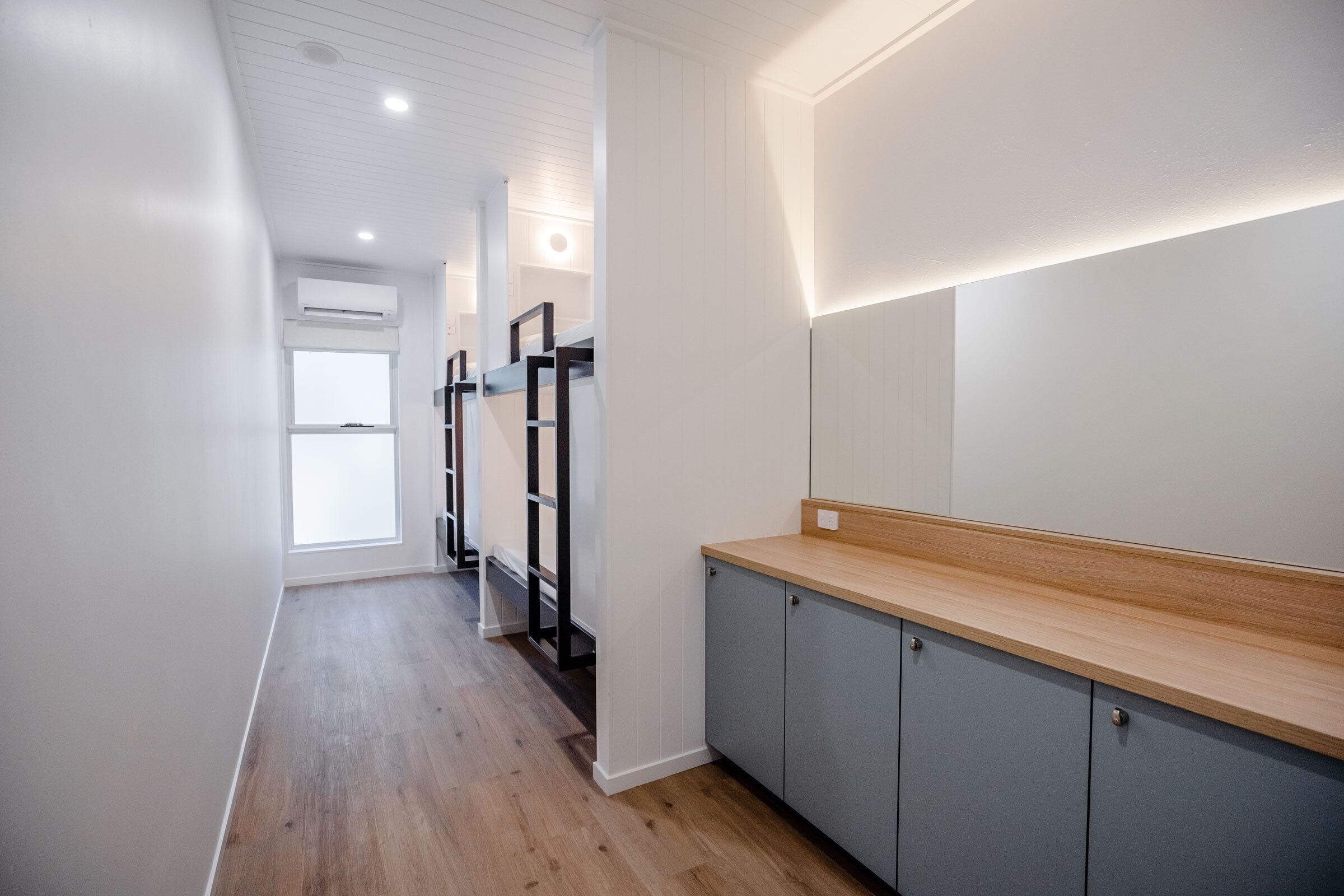 A modern kitchen with grey cabinets, a wooden countertop, and recessed lighting.