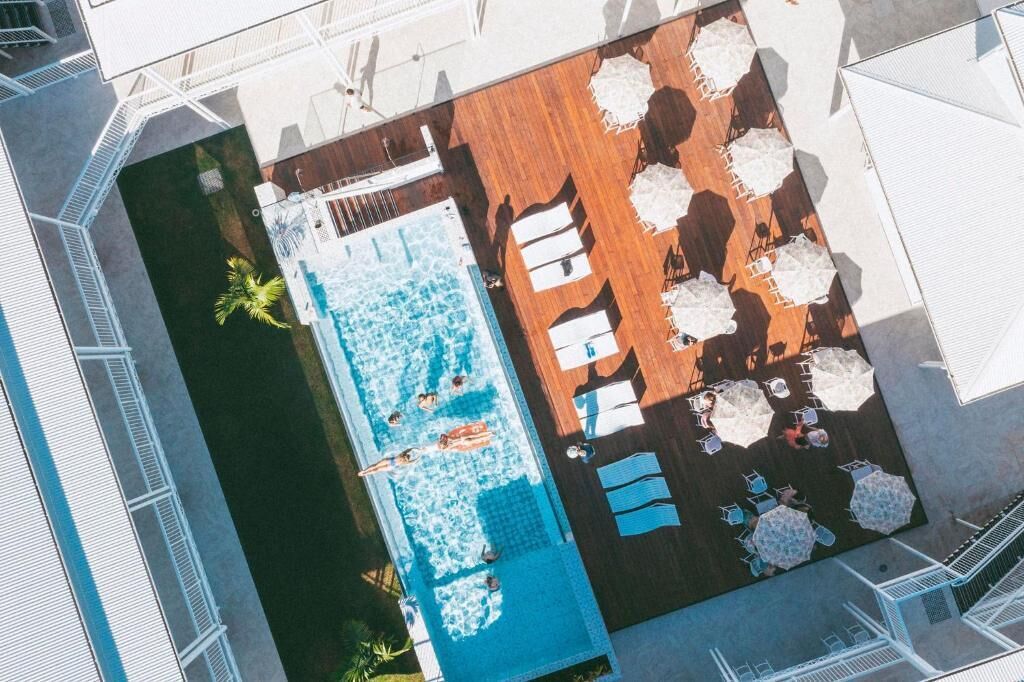Vue aérienne d’un espace piscine avec des chaises longues et des parasols.