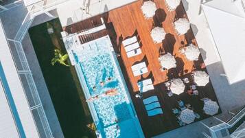 Vue aérienne d’un espace piscine avec des chaises longues et des parasols.
