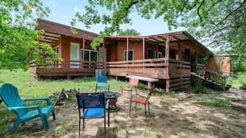 A rustic cabin with a porch, outdoor seating, and a small table.