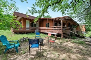 Eine rustikale Holzhütte mit Veranda, Sitzgelegenheiten im Freien und einem kleinen Tisch.