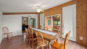Uma área de refeições com mesa e cadeiras de madeira, um ventilador de teto e uma porta de garagem.