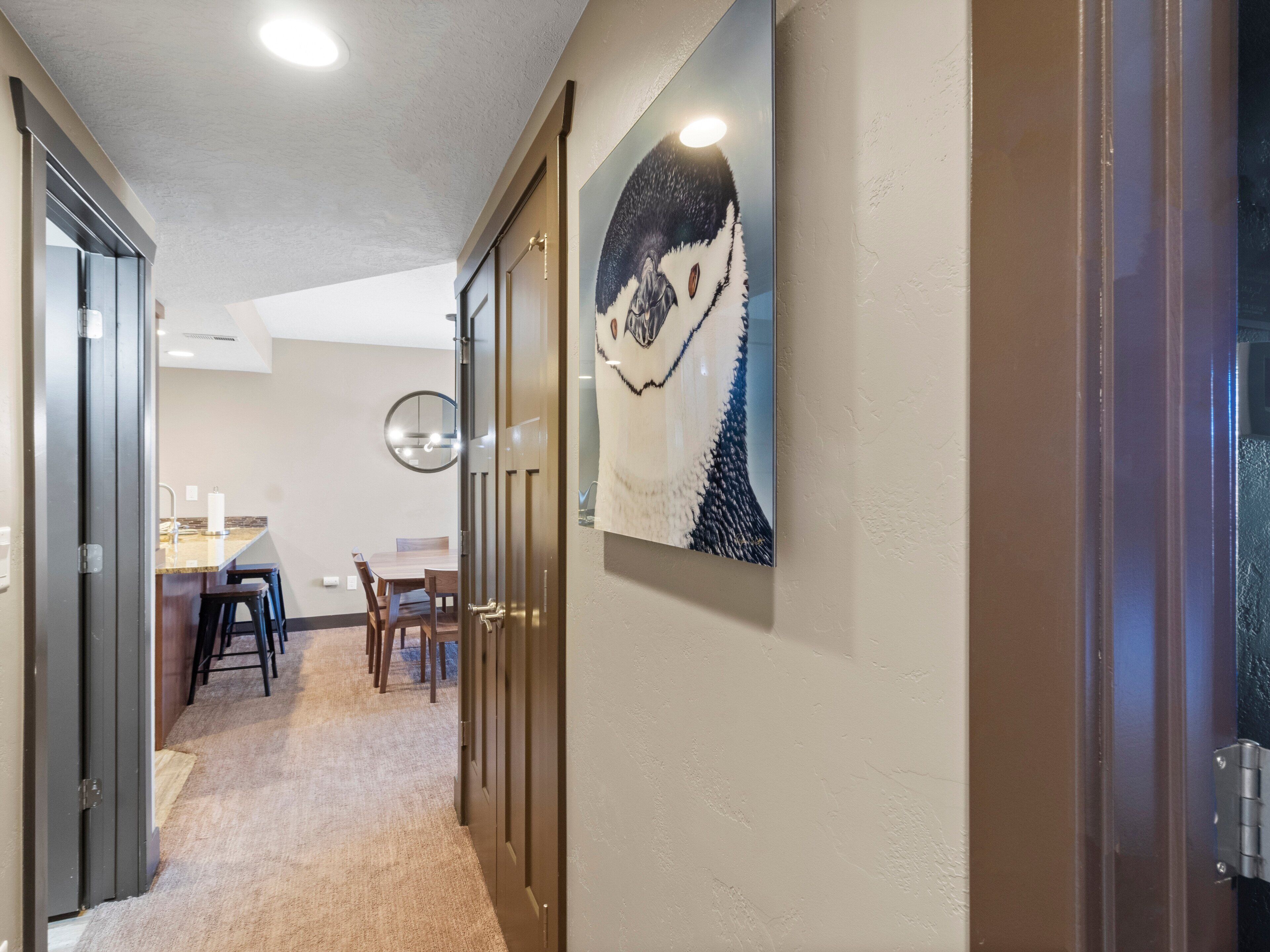 A hallway with a dining area, a painting, and a door.