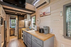 A modern kitchen with wooden cabinetry, a built-in oven, and a coffee maker on the countertop. - 4 Tiny Town + Monthly + Utilities + Comfy Stay (Hico)