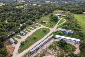 An aerial view of a large property with multiple buildings, a long covered walkway, and a parking area. - 4 Tiny Town + Monthly + Utilities + Comfy Stay (Hico)
