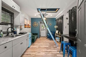 A modern kitchen with white cabinets, a blue countertop, and a wooden floor.
