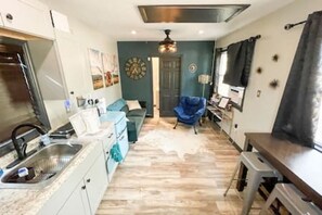A compact living space with a kitchenette, a sofa, a chair, and a dining table.