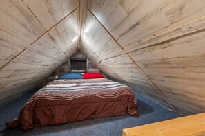 A small, triangular attic bedroom with a single bed, a wooden bench, and a slanted ceiling. - 5 Tiny Town + Monthly + Utilities + Comfy Stay (Hico)