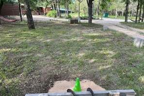 A grassy outdoor area with a wooden bench and a green cone.