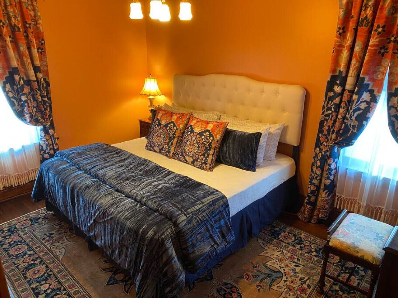 A bedroom with a large bed, a nightstand, a lamp, and a chair.