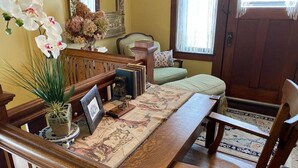 A wooden dining table with chairs, a floral rug, and a potted plant.