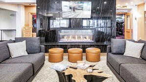 A modern lobby with a large TV screen, a fireplace, leather sofas, and a wooden coffee table. - Shadow Ridge 406 | Walk to Lifts | Mtn Views | Kitchen | Fireplace | Updated | Pool & Hot Tub (Park City)