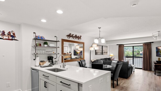 A modern kitchen with a central island, a dining area with a view, and a living space with a balcony. - Shadow Ridge 406 | Walk to Lifts | Mtn Views | Kitchen | Fireplace | Updated | Pool & Hot Tub (Park City)