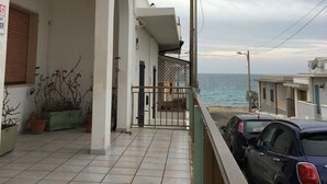 Un bâtiment situé sur la côte, doté d’un balcon carrelé, d’une porte et offrant une vue sur la mer.