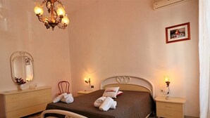 Une chambre à coucher comprenant un lit, des tables de chevet, une commode, un miroir, un lustre et un tableau encadré accroché au mur.