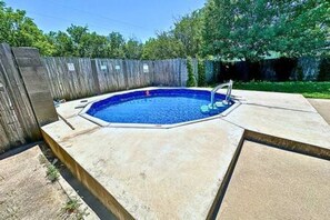 A swimming pool with a wooden deck and a metal ladder. - FW Studio | Pool + Desk | Near TX Speedway (Fort Worth)
