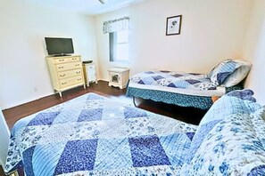 A bedroom with a bed, a dresser, a television, and a window.