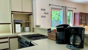 Eine Küche mit Herd, Toaster, Kaffeemaschine und einer Korb voller Gegenstände auf der Arbeitsfläche.