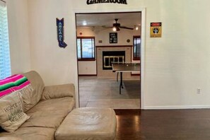 Ein Zimmer mit einer Couch, einem Deckenventilator, einem Kamin und einem Schild mit der Aufschrift 'GAMING ROOM'.