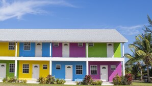 Un edificio colorido de dos pisos con techo plano, varias ventanas y un porche delantero.