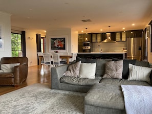 Relax in a spacious living area with a sofa and armchair, adjacent to a dining space with a table and chairs, and a kitchen with modern appliances.