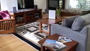 Uma sala de estar com lareira, um sofá, uma mesa de centro e uma televisão.