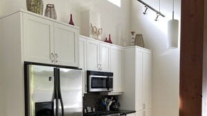 Uma cozinha moderna com armários brancos, eletrodomésticos de aço inoxidável e bancada preta.