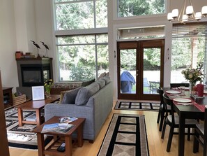 Amplia sala de estar con chimenea, un sofá, una mesa de centro y un comedor con una mesa preparada para dos personas.