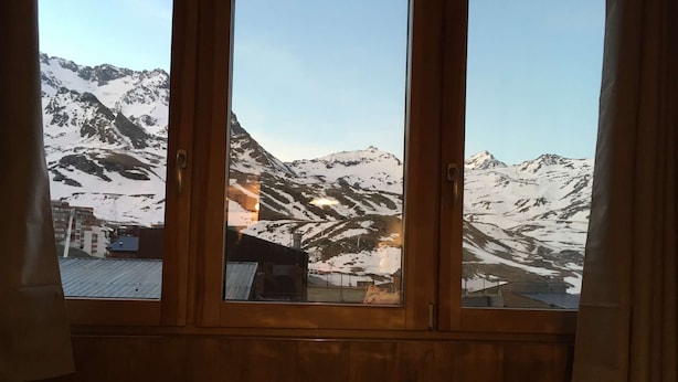 Una habitación con un amplio ventanal que ofrece vistas a montañas nevadas y edificios.