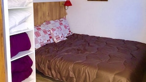 Un dormitorio con cama, armario y dos cuadros en la pared.