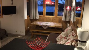Una habitación acogedora con una mesa de madera, televisor y cafetera.