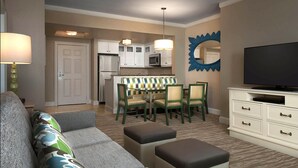 A compact living space with a sofa, ottomans, a dining table with chairs, a kitchen area, and a television on a cabinet. - OCEANFRONT Marriott's OceanWatch Resort, 2BR2BA Garden view Villa NO clean fee (Myrtle Beach)