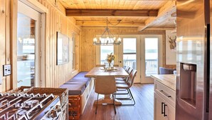 A wooden interior with a dining table, bench seating, and a stainless steel refrigerator. - Updated Glen Arbor Cottage on Lake: Dock & Mooring (Glen Arbor)